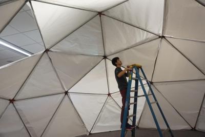 A student stands on a ladder inside the dome which is mostly covered with white plastic panels.