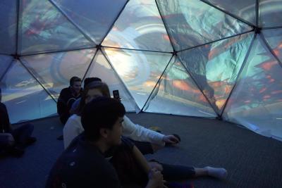 Students sit inside the dome while a video plays across the surface.