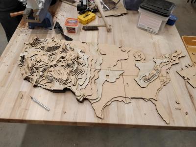 A topographic map of the US made from stacked sections of plywood.