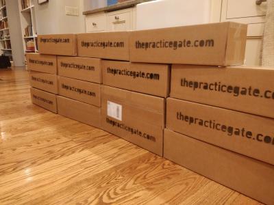 An wall of 14 sealed cardboard boxes, each reading 'thepracticegate.com'.